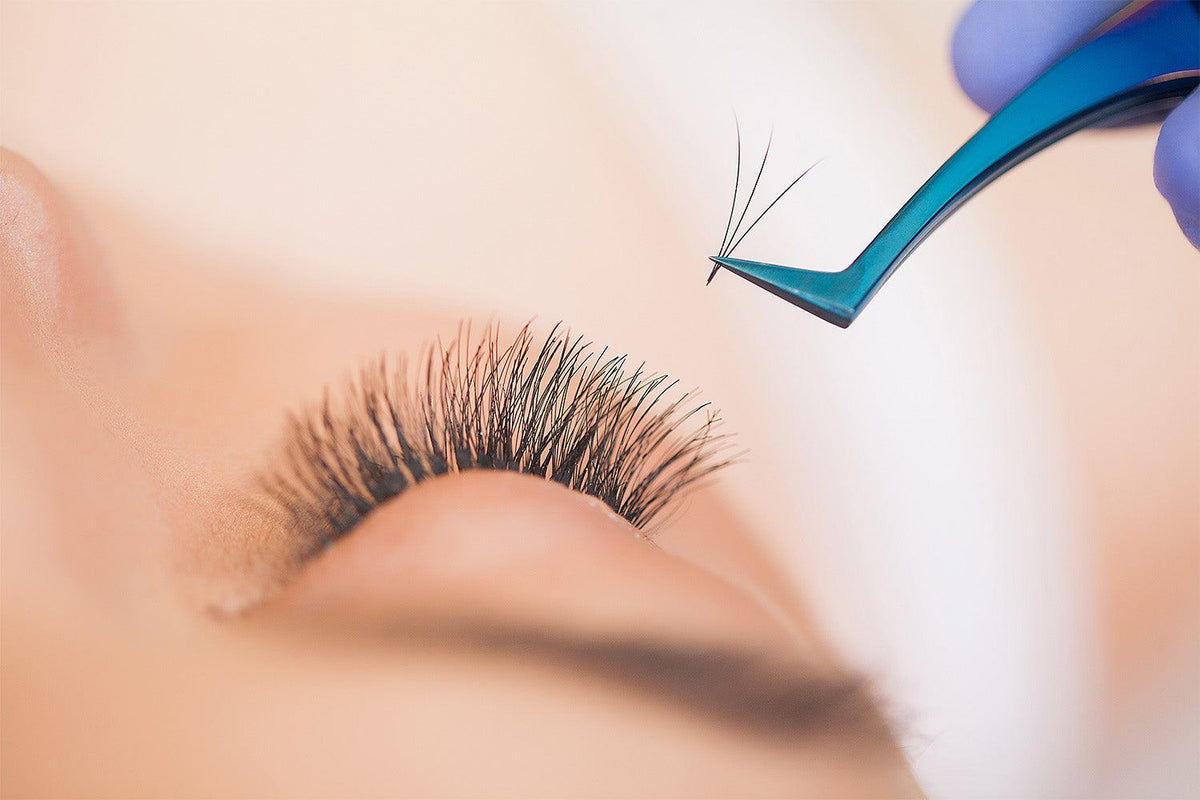Woman caring for her eyelash extensions with a lash comb and gentle cleanser